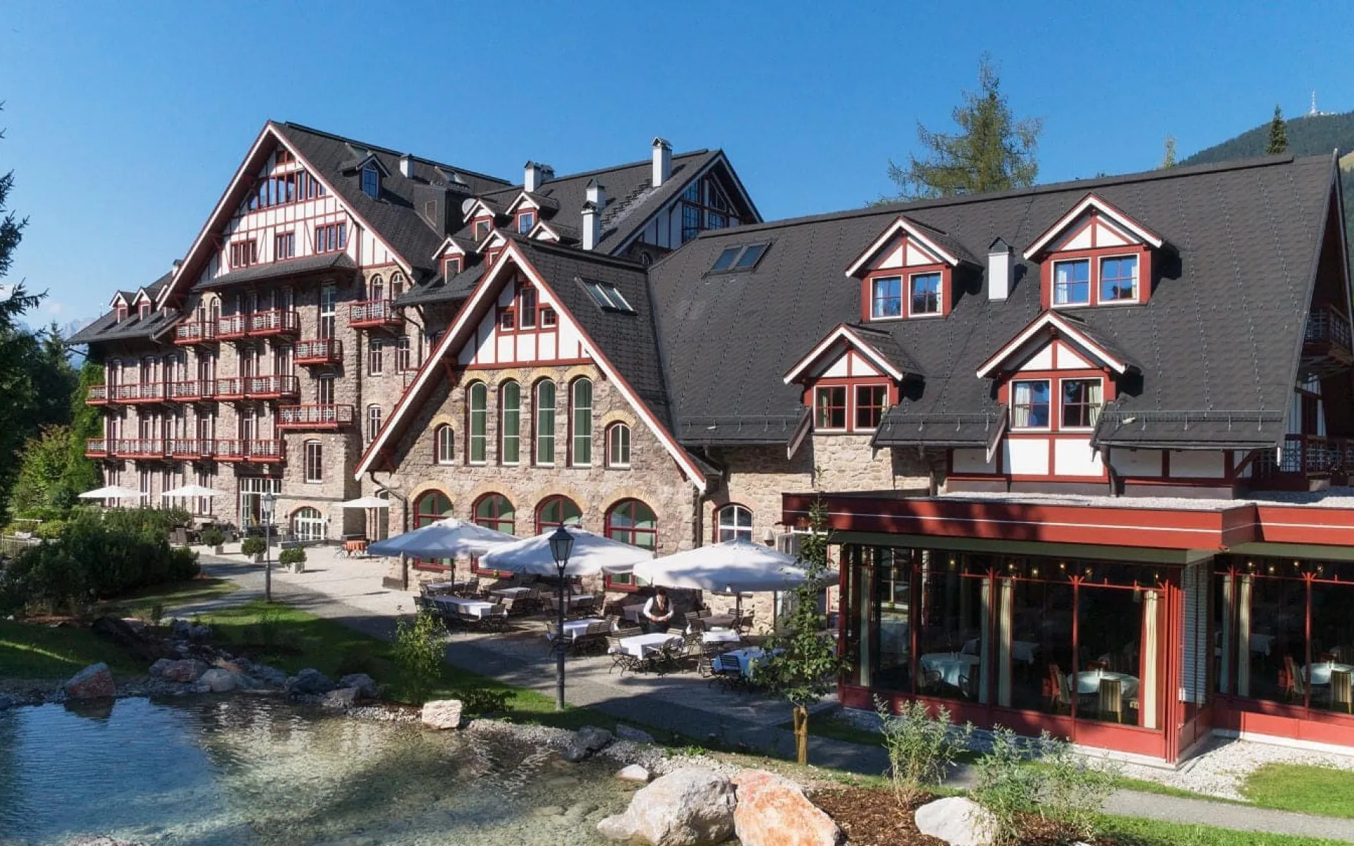 Luxurious Grand Hotel Kitzbühel with mountain backdrop and garden.